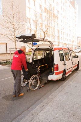 conducteur Optibus aidant une personne en fauteuil roulant à monter la rampe du véhicule optibus.